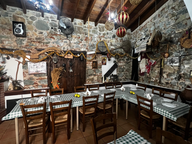 Rustic restaurant with stone walls and wooden chairs.